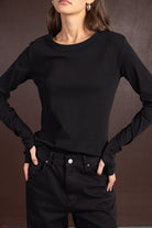 אישה לובשת חולצה שחורה ארוכה ומכנסי ג'ינס שחורים, אופנת נשים צעירה ואלגנטית