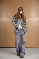 דוגמנית צעירה עם חולצת פלאנל משובצת, ג'ינס רחב, ונעלי חום, לוק קז'ואל אופנתי לנשים