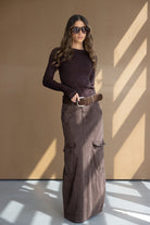 דוגמנית עם חולצה סריג חומה וחצאית מקסי חומה עם כיסים, חגורה חומה ומשקפי שמש אופנתיים