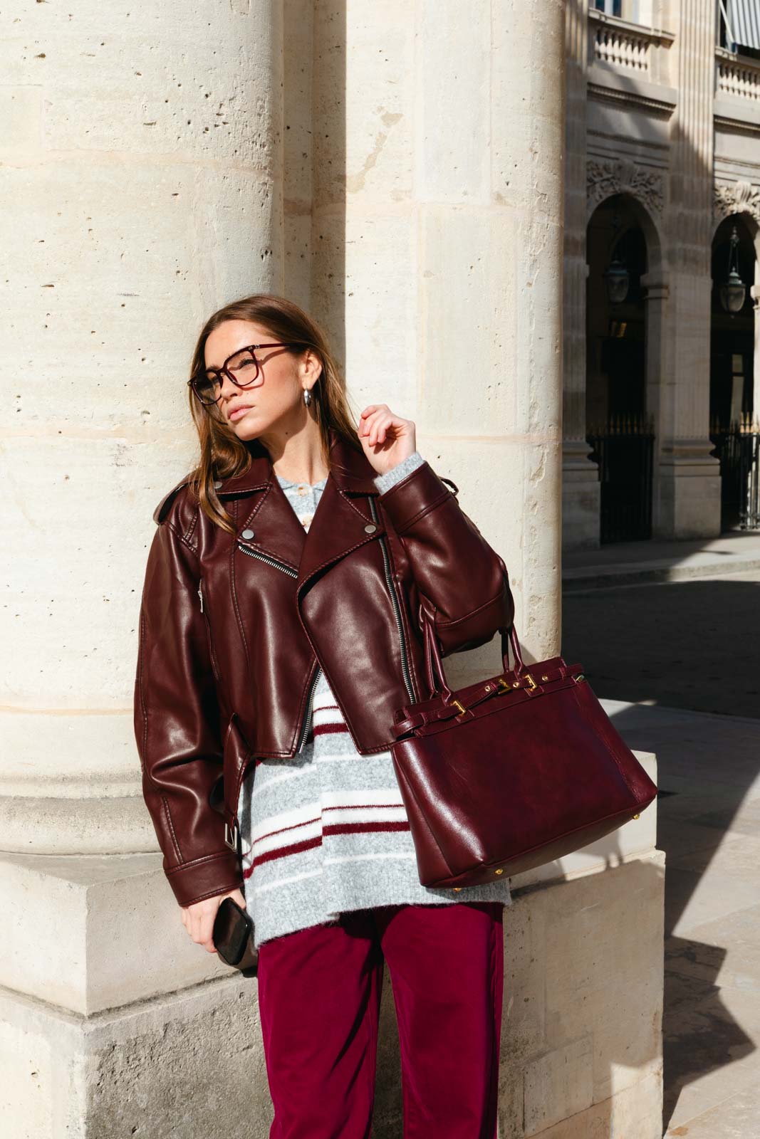 אישה עם ז'קט עור בורדו, מכנסיים תואמים ותיק אופנתי, לוק חורף עירוני לנשים