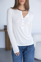 אישה לובשת חולצת כפתורים לבנה עם שרוול ארוך ומכנסי ג'ינס, אופנת נשים עדכנית