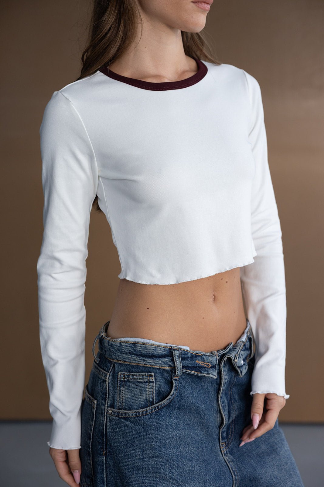 דוגמנית לובשת חולצת קרופ לבנה עם שרוולים ארוכים וג'ינס גבוה, אופנת נשים וצעירות