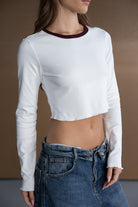 דוגמנית לובשת חולצת קרופ לבנה עם שרוולים ארוכים וג'ינס גבוה, אופנת נשים וצעירות