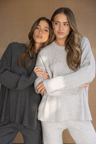 שתי נשים בדגמים סריג ריב אופנתיים, אחת בחליפת סריג אפורה ואחת בחליפת סריג כהה