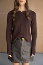 חולצת סריג חומה עם כפתורים וחצאית מיני דמוי עור, לוק אופנתי לנשים