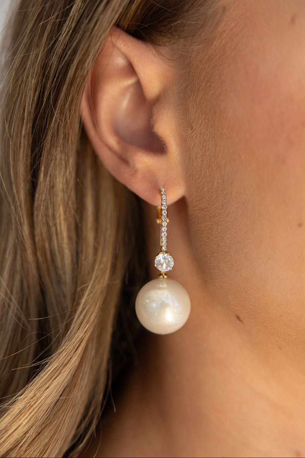 עגיל זהב תלוי משובץ קוביות זירקוניה עם תליון פנינה לאישה, תקריב על האוזן