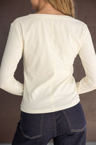 חולצת נשים ארוכה בצבע שמנת עם תפר מרכזי, ג'ינס כהה, מראה אחורי אופנתי