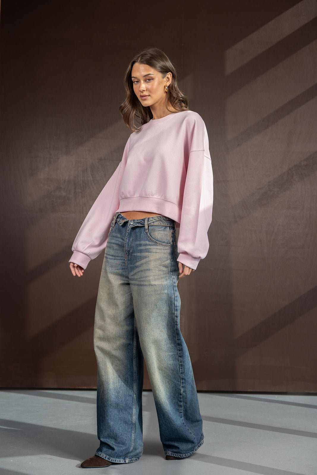 דוגמנית לובשת סווטשירט ורוד קרופ ומכנסי ג'ינס רחבים אופנתיים לנשים