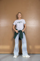 אישה עם חולצת טי שירט אפורה, מכנסי ג'ינס רחבים, סווטשרט ירוק קשור, נעלי סניקרס אופנה